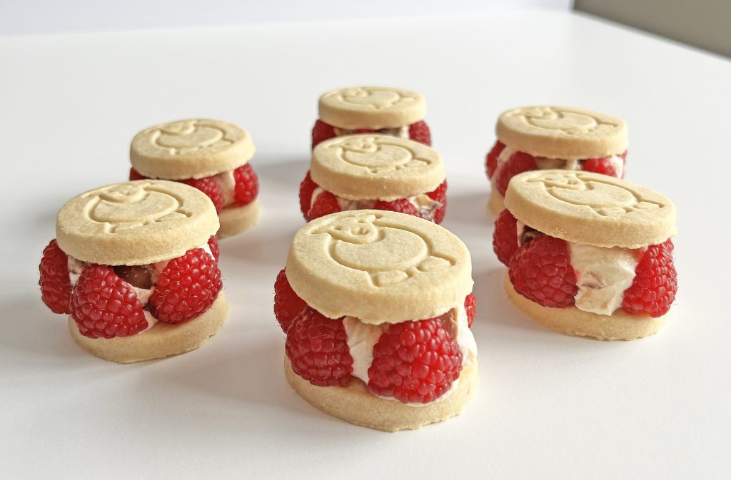 Chocolate ripple cheesecake mixture sandwiched between two Herdy Shortbreads surrounded by fresh raspberries